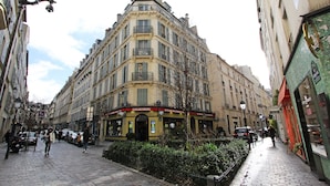 Un immeuble d’angle dont le rez-de-chaussée abrite un café appelé « Goldenberg ».