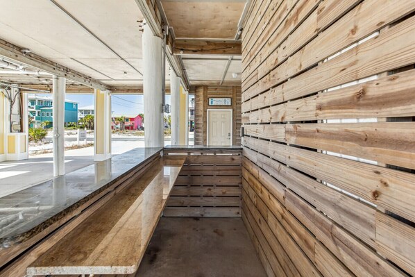 A corridor with wooden paneling, concrete pillars, and a view of the outside.