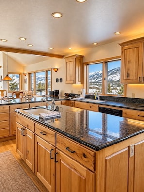A spacious kitchen with wooden cabinets, a large island, and a view of snow-capped mountains. - Ski-in, Quick Walk to Slopes with AMAZING VIEWS (Mt Crested Butte)
