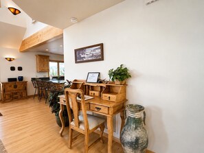 A wooden dining table with chairs, a vase, and a framed certificate on a desk.
