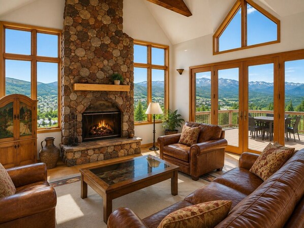 A spacious living room with a stone fireplace, leather furniture, and large windows offering mountain views. - Ski-in, Quick Walk to Slopes with AMAZING VIEWS (Mt Crested Butte)