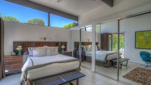A modern bedroom with a large bed, a bench, a mirror, and a view of the outdoors. - PS Butterfly: Well-Styled, Authentic Mid-Century Home (Palm Springs)