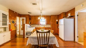 Una cocina con paredes de madera, una mesa de comedor con sillas, un refrigerador y una ventana con luz natural.