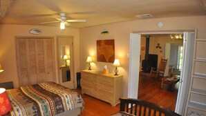 Un dormitorio con dos camas, un aparador, un ventilador de techo y un televisor en la habitación contigua.