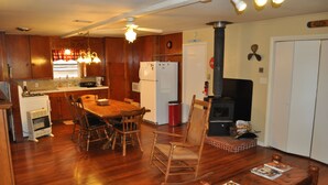 Una cocina compacta con armarios de madera, una mesa de comedor y un estufa a leña.