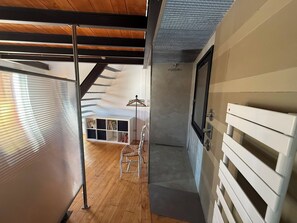 A room with a sloped ceiling, a wooden floor, a white radiator, and a bookshelf with books. - Stunning and spacious home in Provence!  (Lourmarin)