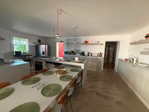 A modern kitchen with a central island, dining area with chairs, and a view of the outdoors. - Stunning and spacious home in Provence! (Lourmarin)