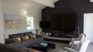 Ein modernes Wohnzimmer mit einem grauen Sofa, einem gestreiften Sessel, einem schwarzen Couchtisch und einem Kamin.