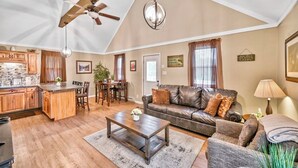 A spacious living area with a dining table, leather sofa, and a kitchen with wooden cabinets. - Beach/Lake Home In Towamensing Trails (Albrightsville)