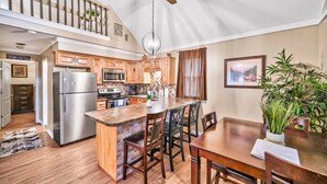A spacious kitchen with wooden cabinets, a stainless steel refrigerator, and a dining area with a wooden table and chairs. - Beach/Lake Home In Towamensing Trails (Albrightsville)