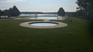 A swimming pool with a surrounding grassy area and a view of a body of water. - Beach/Lake Home In Towamensing Trails (Albrightsville)