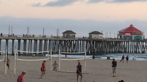 A beach volleyball game on a sandy court with a wooden pier and buildings in the background. - "Welcome to Your Ultimate Huntington Beach Get-a-way! 3-Blocks to the Beach!  (Huntington Beach)
