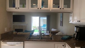A kitchen with white cabinets, a dishwasher, a coffee maker, and a window overlooking a patio area. - "Welcome to Your Ultimate Huntington Beach Get-a-way! 3-Blocks to the Beach!  (Huntington Beach)