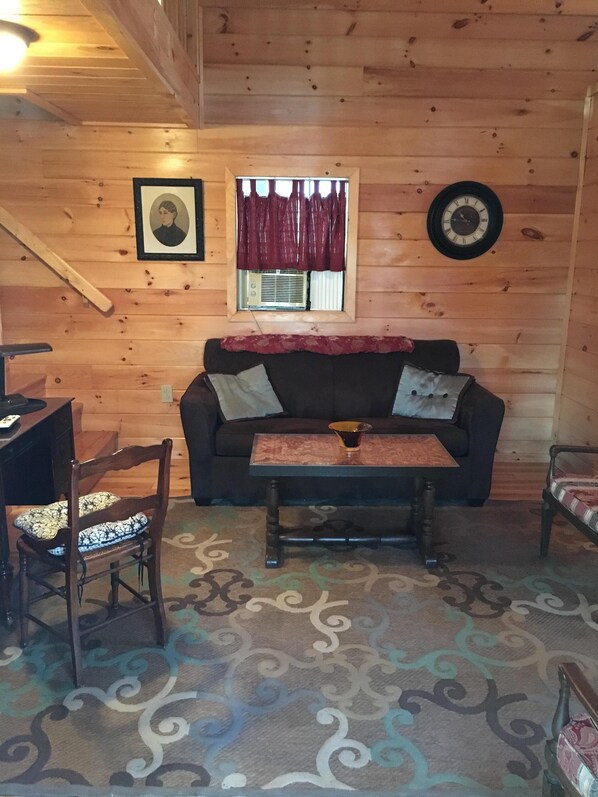 A wooden interior with a sofa, a table, and a chair.
