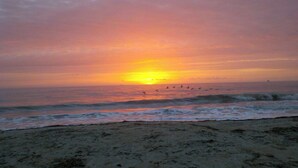 Ein Strand mit Wellen und einem Sonnenuntergang.