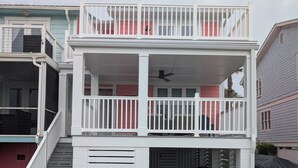 Ein zweistöckiges Gebäude mit Balkon, Treppe und überdachtem Bereich.