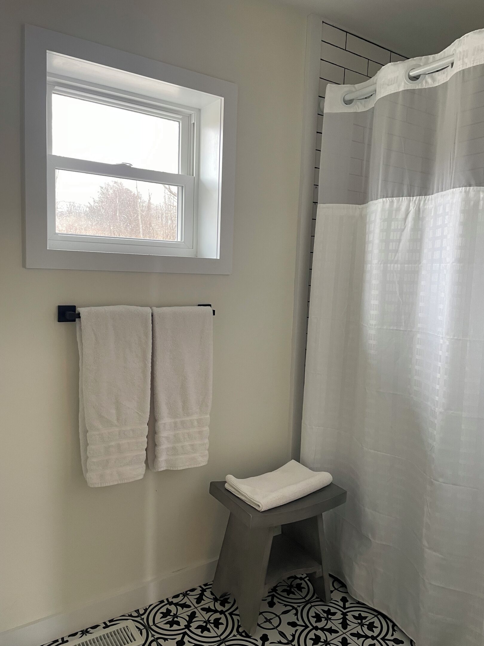 Une salle de bain avec une fenêtre, un rideau de douche et un porte-serviettes.