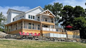 A multi-story house with a covered porch, stone retaining wall, and a red umbrella. - VRFLX Seneca View Villa | Walk to Wineries (Burdett)