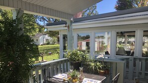 Un patio techado con una mesa y sillas, plantas en macetas y vistas al vecindario.