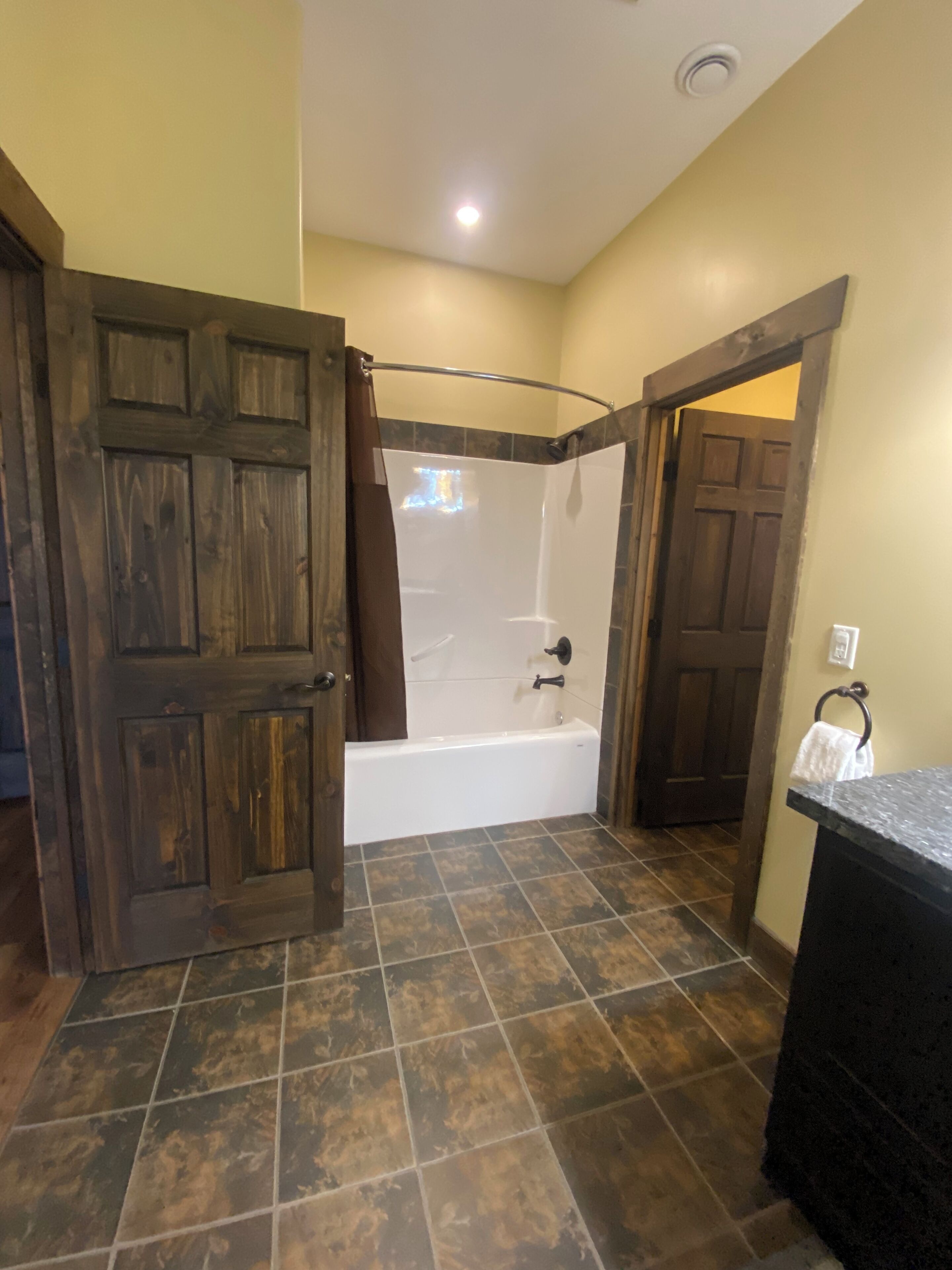 A bathroom with a bathtub, a shower, and a wooden door.