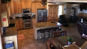 A spacious kitchen with wooden cabinets, stainless steel appliances, and a central island with bar stools. - Remote ranch house on 93 acres in the peaceful Indianola Valley! Sleeps 30 (Fairview)