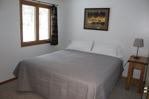 Cozy retreat with a large bed, framed picture, and wooden nightstand.