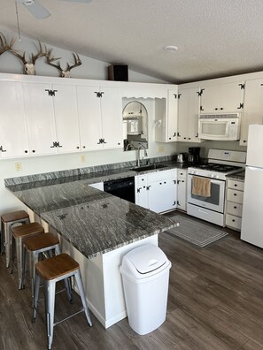 Enjoy cooking in this well-equipped kitchen with a central island, sink, microwave, oven, and dishwasher.