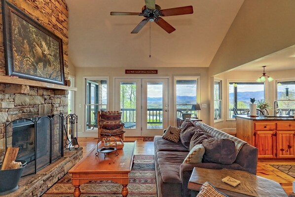 A spacious living room with a stone fireplace, a wooden coffee table, and a comfortable sofa.