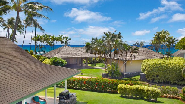 A resort with multiple buildings, a covered patio area, and a well-maintained lawn with tropical plants.