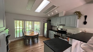 Una cocina con mesa, refrigerador, estufa y lavaplatos.