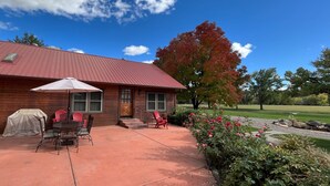 Una cabaña de madera con techo rojo, mobiliario de patio y una mesa cubierta.