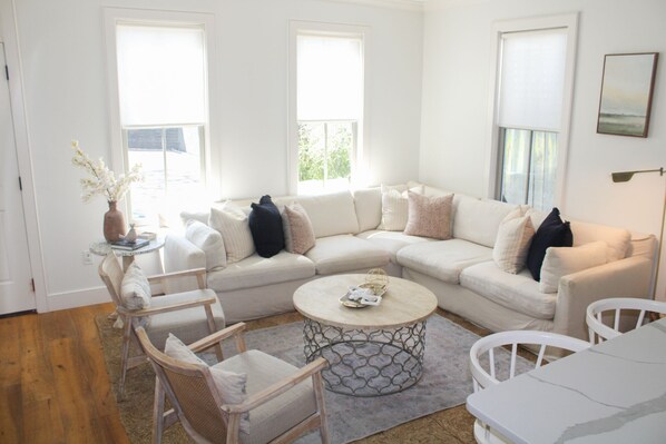 A living room with a white sectional sofa, two armchairs, a coffee table, and a vase with flowers.