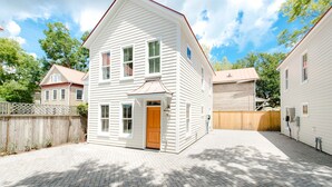 A two-story house with a front porch, a wooden fence, and a paved driveway. - Guesthouse Charleston: WEST (242 B) (Charleston)