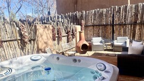A hot tub with a rustic wooden fence and outdoor furniture in the background.