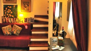 Una sala de estar acogedora con un sofá rojo, una mesa de centro y una escalera que sube a otro nivel.