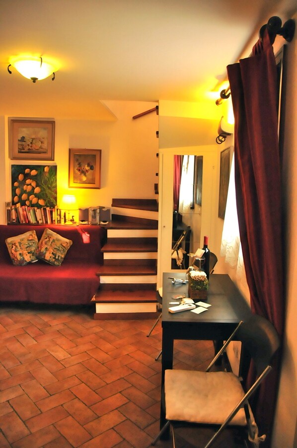 Un salon chaleureux avec un canapé rouge, une table basse et un escalier menant à un autre niveau.