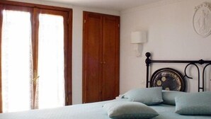 Un dormitorio con cama, armario de madera y una lámpara fijada a la pared.