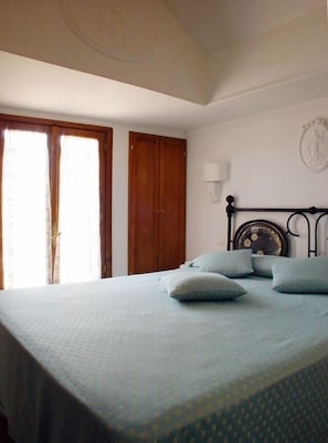 Une chambre à coucher avec un lit, une armoire en bois et une lampe fixée au mur.