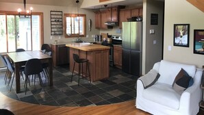 A modern kitchen with a central island, wooden cabinets, and a stainless steel refrigerator. - Beautiful Cottage on Private Lake close to Manistee  (Wellston)