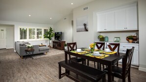 A modern living room with a dining area, featuring a sofa, dining table, and a bench.