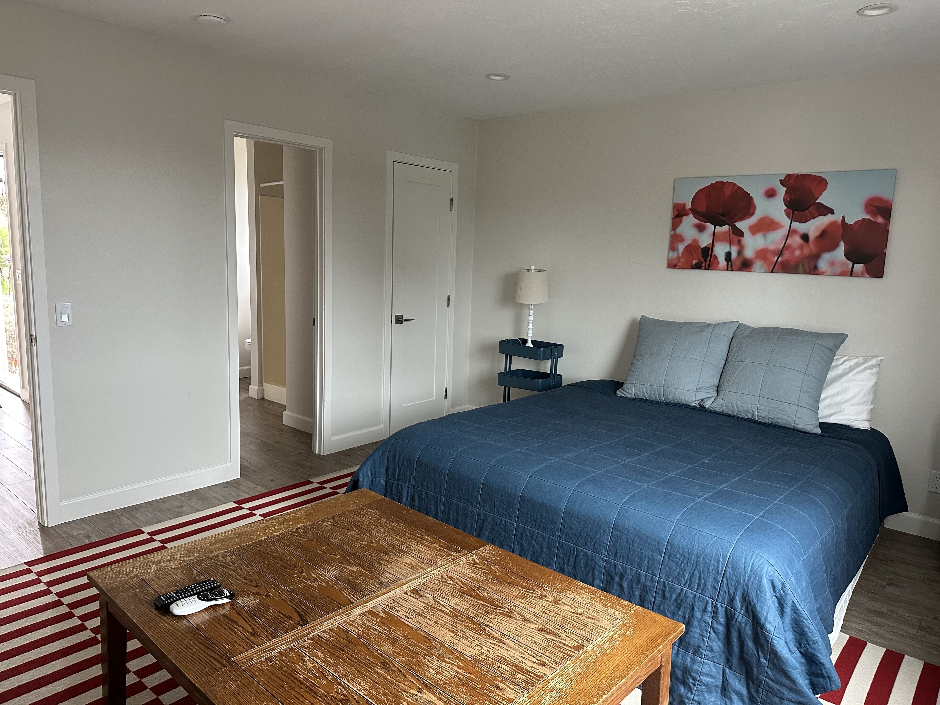 Een slaapkamer met een bed, nachtkastje, lamp, salontafel en een schilderij aan de muur.