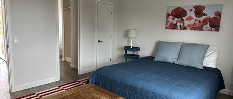 Een slaapkamer met een bed, nachtkastje, lamp, salontafel en een schilderij aan de muur.
