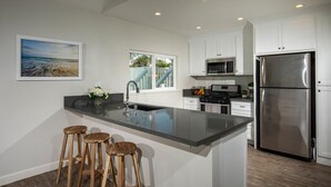 A modern kitchen with a large island, stainless steel appliances, and wooden bar stools.