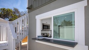 A modern kitchen with a built-in microwave and a small window overlooking a deck.