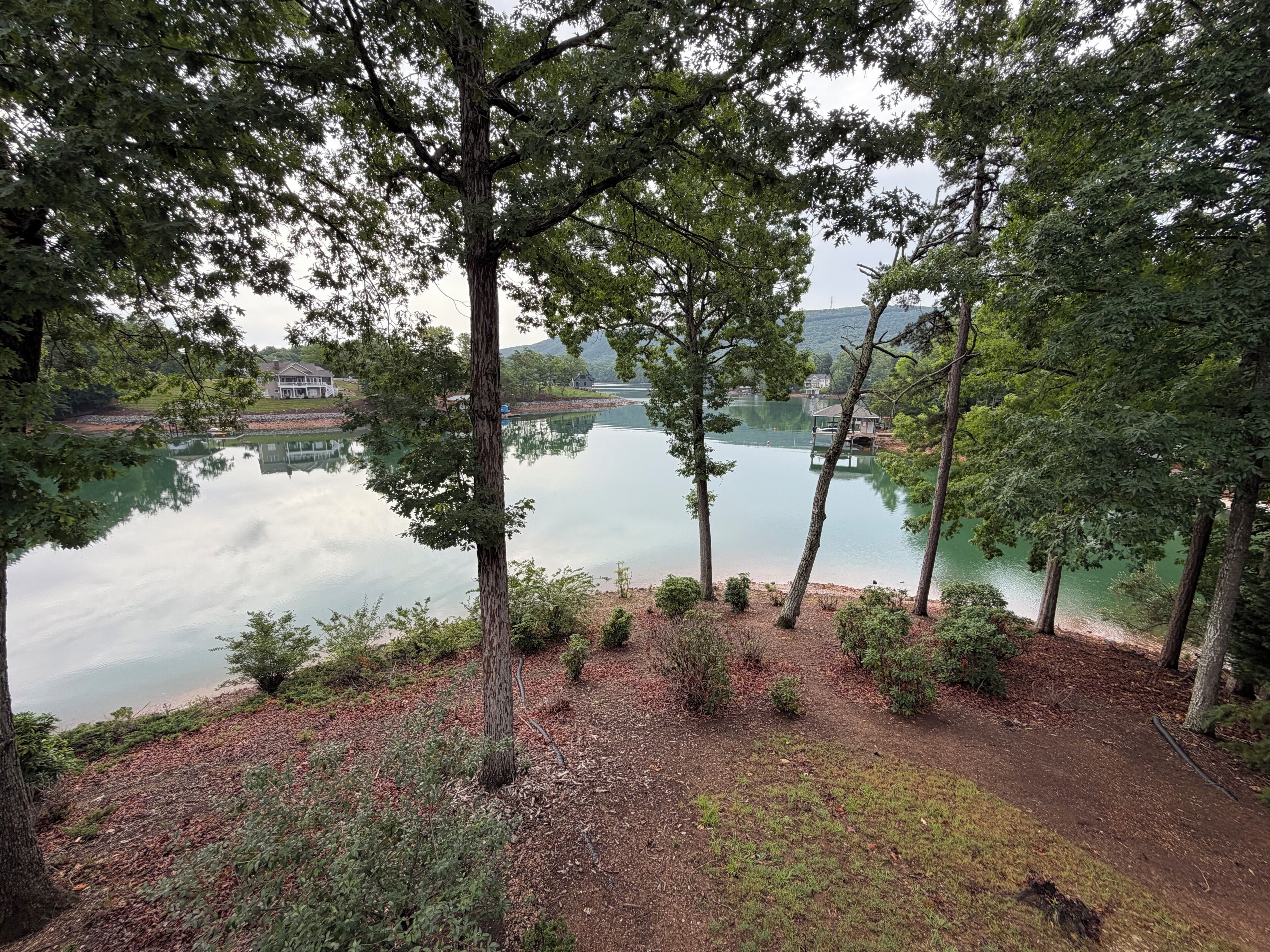 A lakeside view with trees, a gazebo, and a dock.