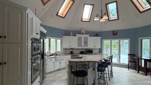 A spacious kitchen with skylights, a central island with bar stools, and a view of the outdoors. - Wind Family Estate--7000sq feet with 7 flex rooms! (Huddleston)