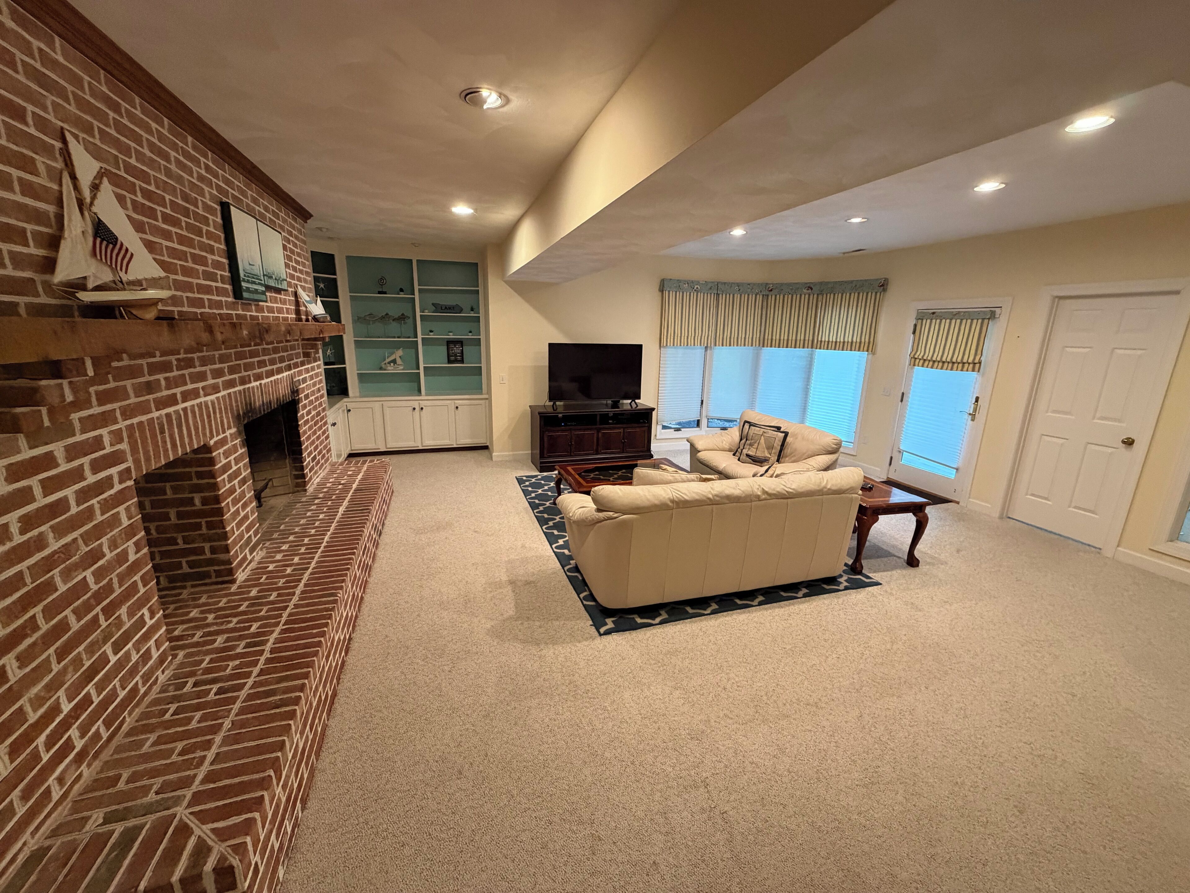A living room with a brick fireplace, a sofa, a television, and a bookshelf.