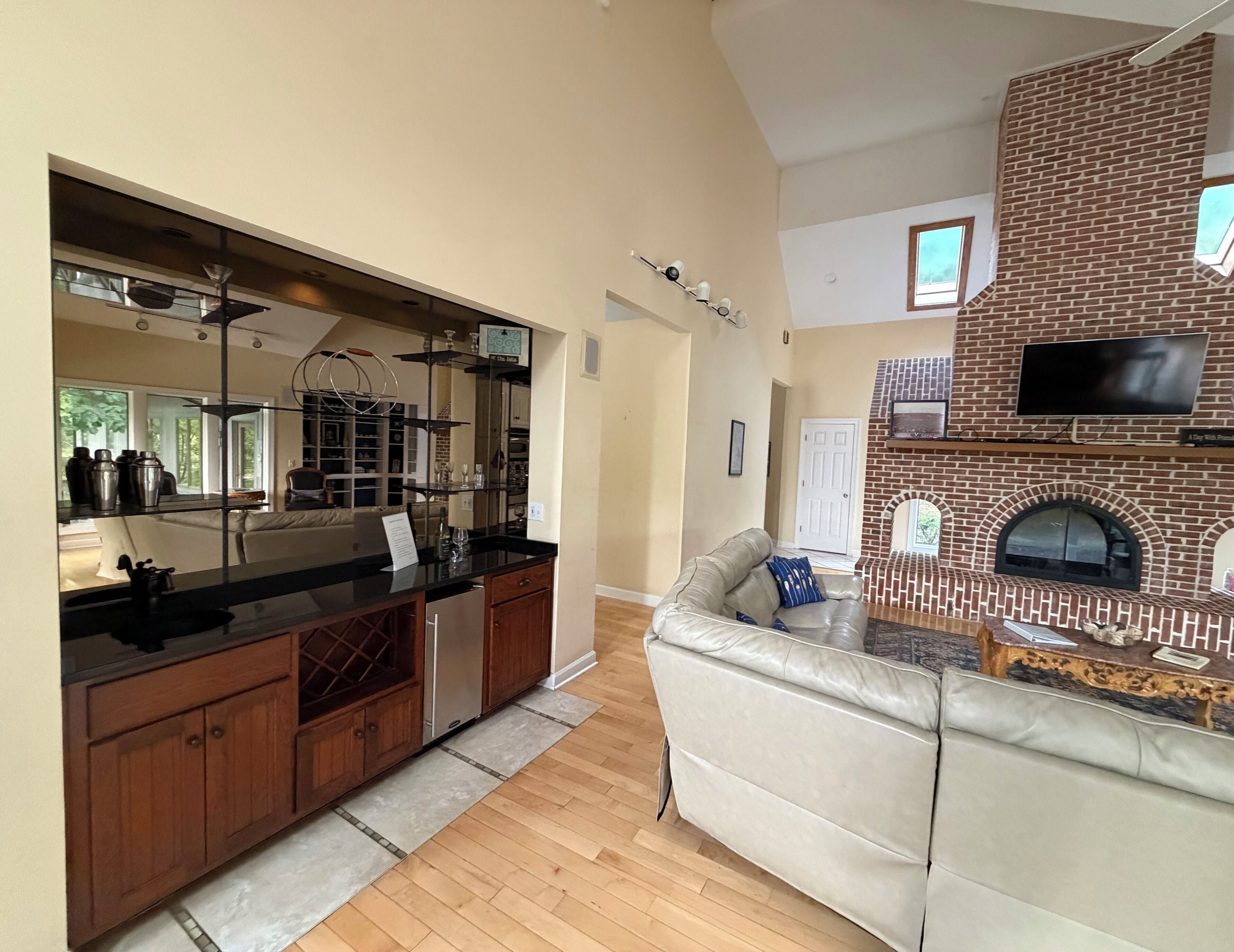 A modern kitchen with a large island, a brick fireplace, and a cozy seating area.