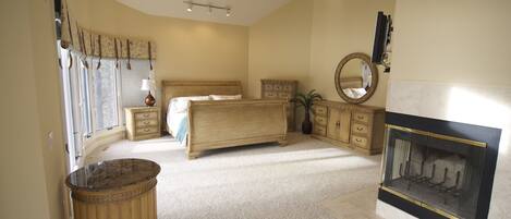 Un dormitorio con cama, cómoda, espejo y chimenea.