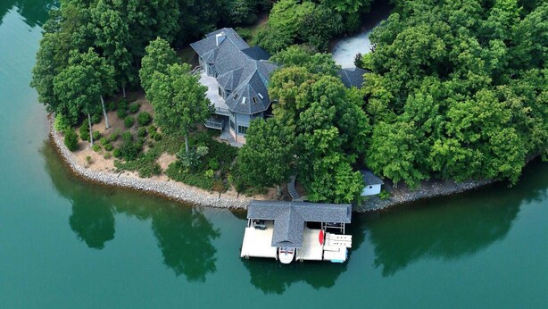 An aerial view of a house surrounded by dense trees and a dock with a boat. - Wind Family Estate--7000sq feet with 7 flex rooms! (Huddleston)